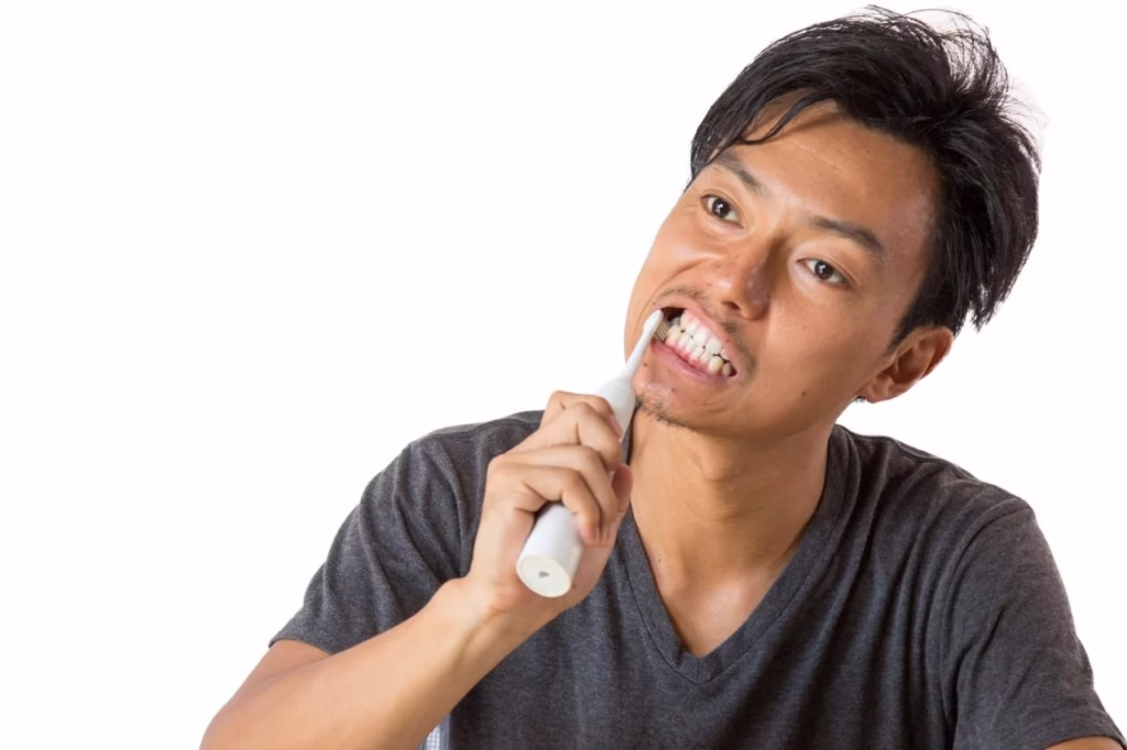 電動歯ブラシで歯磨きする男